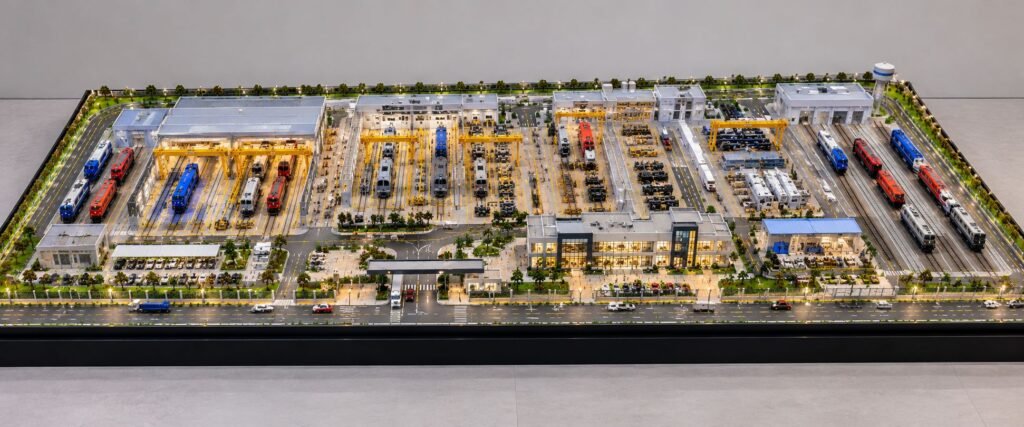 Locomotive manufacturing facility physical scale model with railway tracks, factory buildings, miniature locomotives and industrial machinery